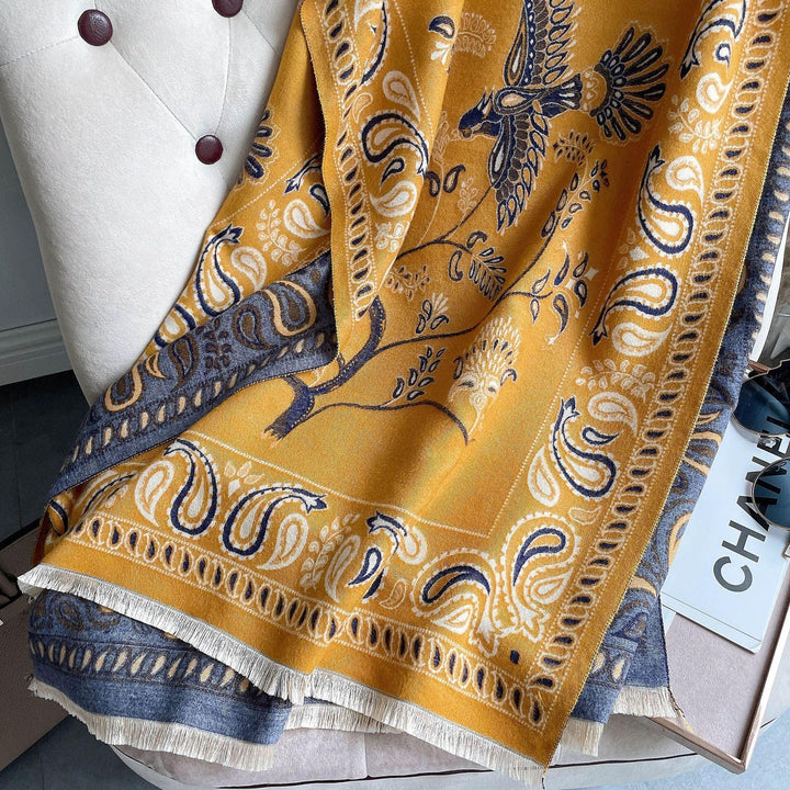 Yellow and blue paisley patterned scarf with bird and floral designs draped on tufted chair