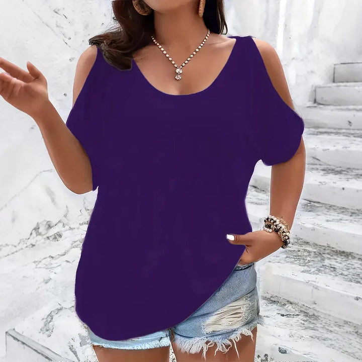 Woman wearing purple cold shoulder top with ripped denim shorts and gold jewelry on marble stairs