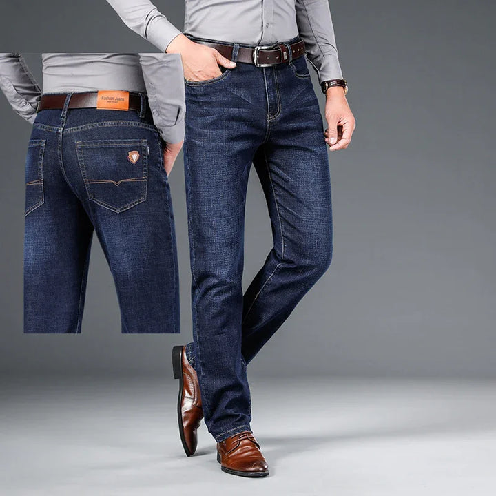 Men's dark blue slim-fit jeans styled with brown belt and brown leather dress shoes