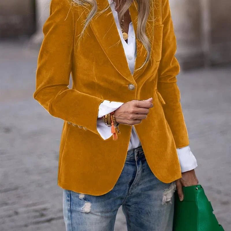 Woman wearing mustard yellow velvet blazer with white shirt and ripped jeans holding green handbag