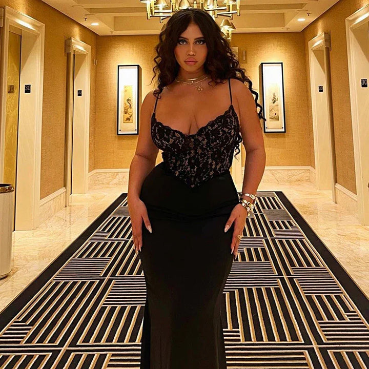 Woman in elegant black lace top and long skirt posing in hotel hallway with patterned carpet