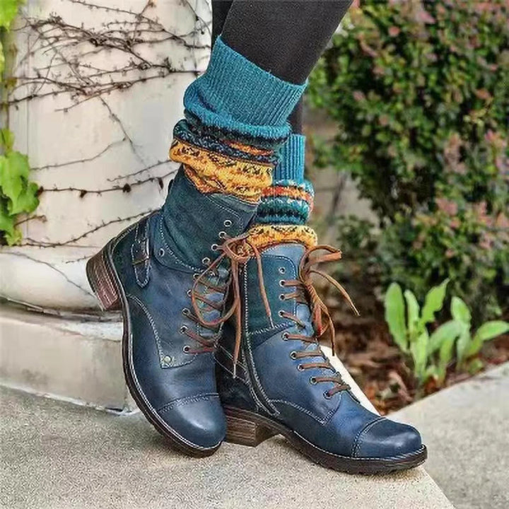 Stylish navy blue leather lace-up boots worn with colorful knitted socks outdoors on concrete steps