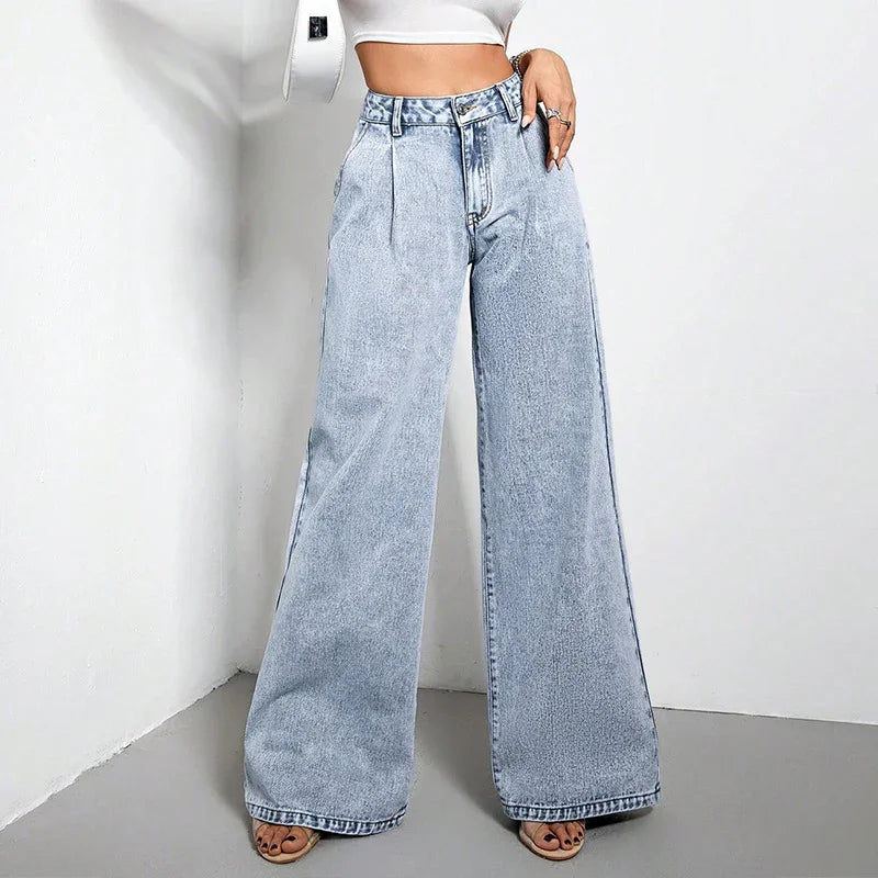 Woman wearing high-waisted light blue wide-leg denim jeans and white crop top in a minimal studio