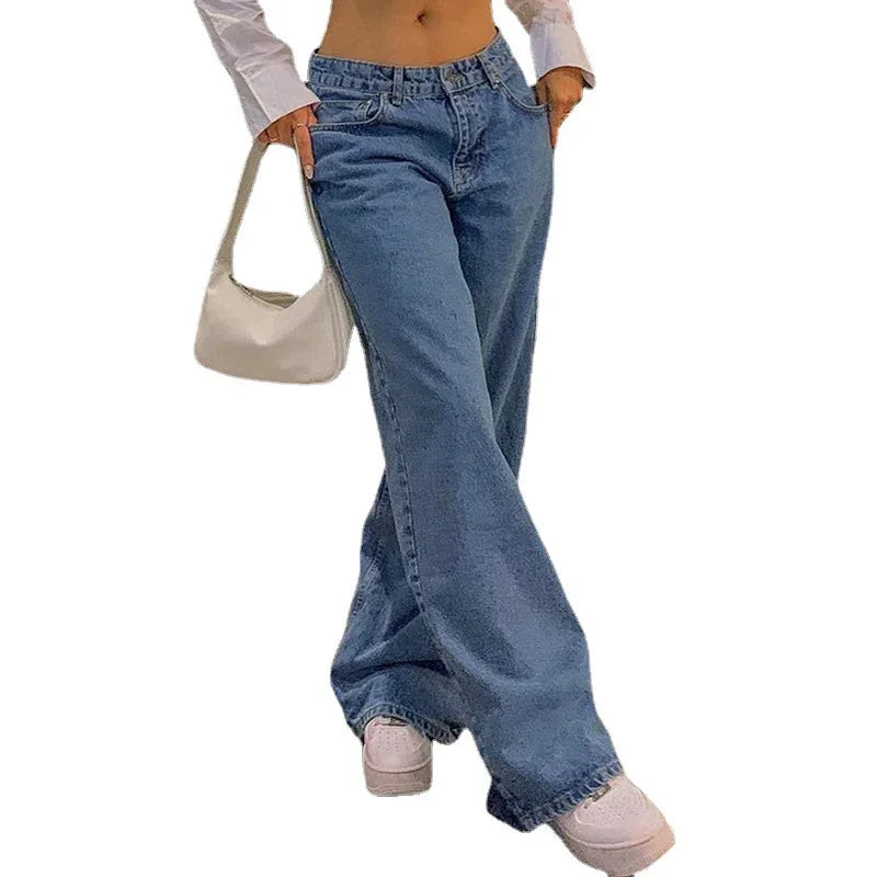 Woman wearing loose-fit blue jeans, white crop top, white sneakers, and carrying a small white handbag