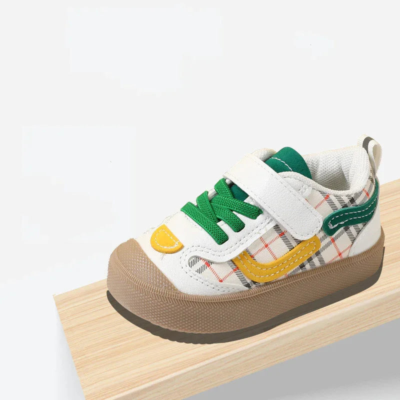 Colorful toddler sneaker with green laces, yellow and green accents, plaid pattern, and brown sole