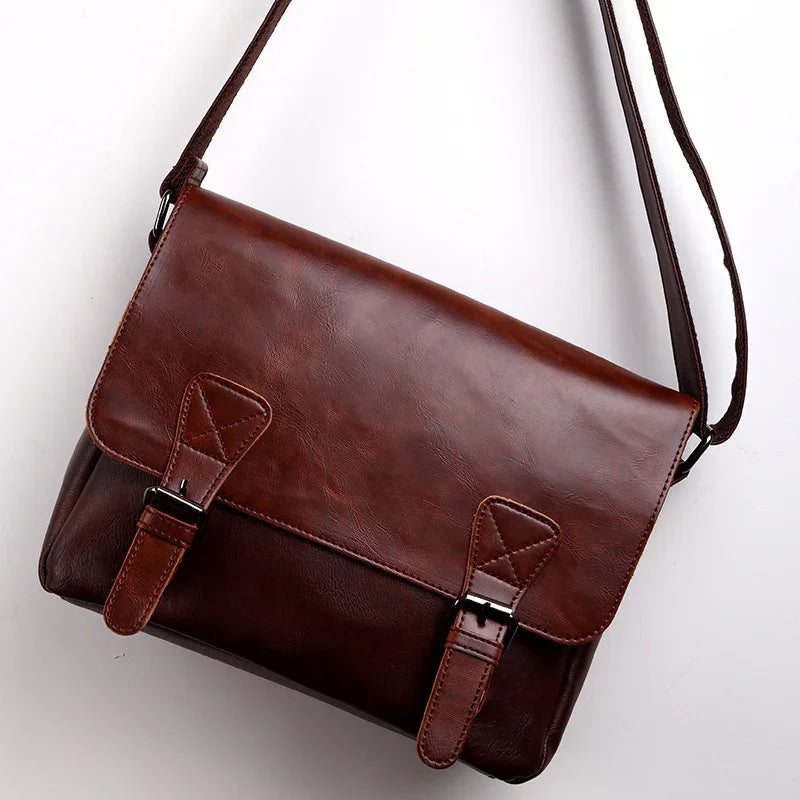 brown leather messenger bag with adjustable strap and buckle closures on white background