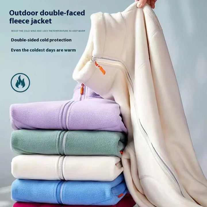 Stack of colorful outdoor double-faced fleece jackets with a cream jacket held up, highlighting warmth and cold protection