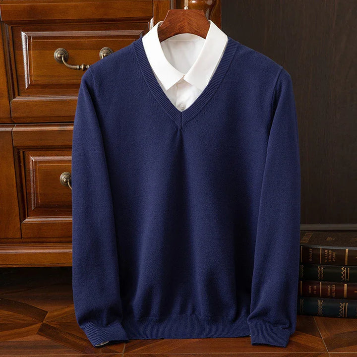 Navy blue V-neck sweater layered over white collared shirt on wooden hanger, classic men's fashion