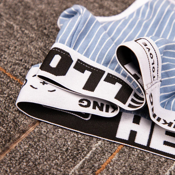 Close-up of blue and white striped boxer briefs with bold black and white elastic waistband on carpet