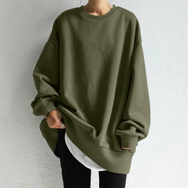 Person wearing oversized olive green sweatshirt with long sleeves over white shirt and black pants