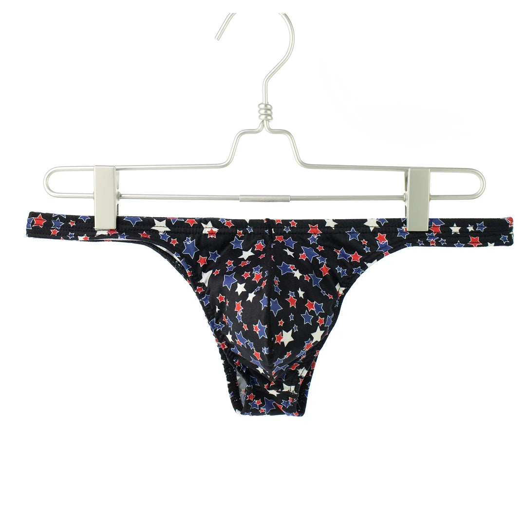 Men's black bikini briefs with red, white, and blue stars pattern hanging on metal hanger