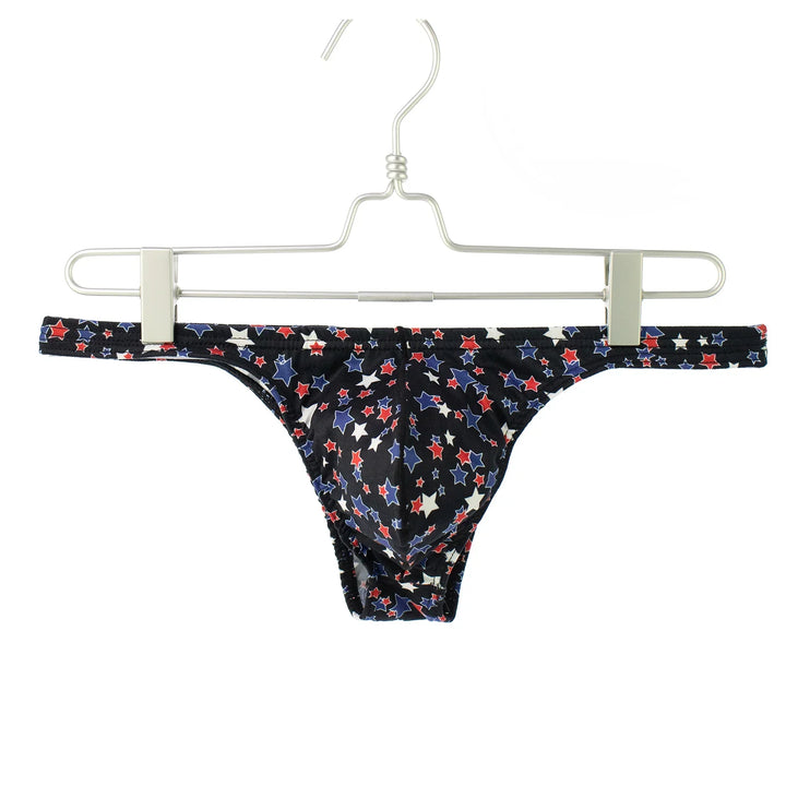 Men's black bikini briefs with red, white, and blue stars pattern hanging on metal hanger