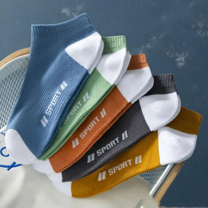 Set of colorful ankle sport socks in blue, green, orange, gray, and yellow on a chair