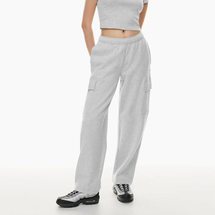 Woman wearing light gray cargo sweatpants and crop top, sporty casual outfit on white background