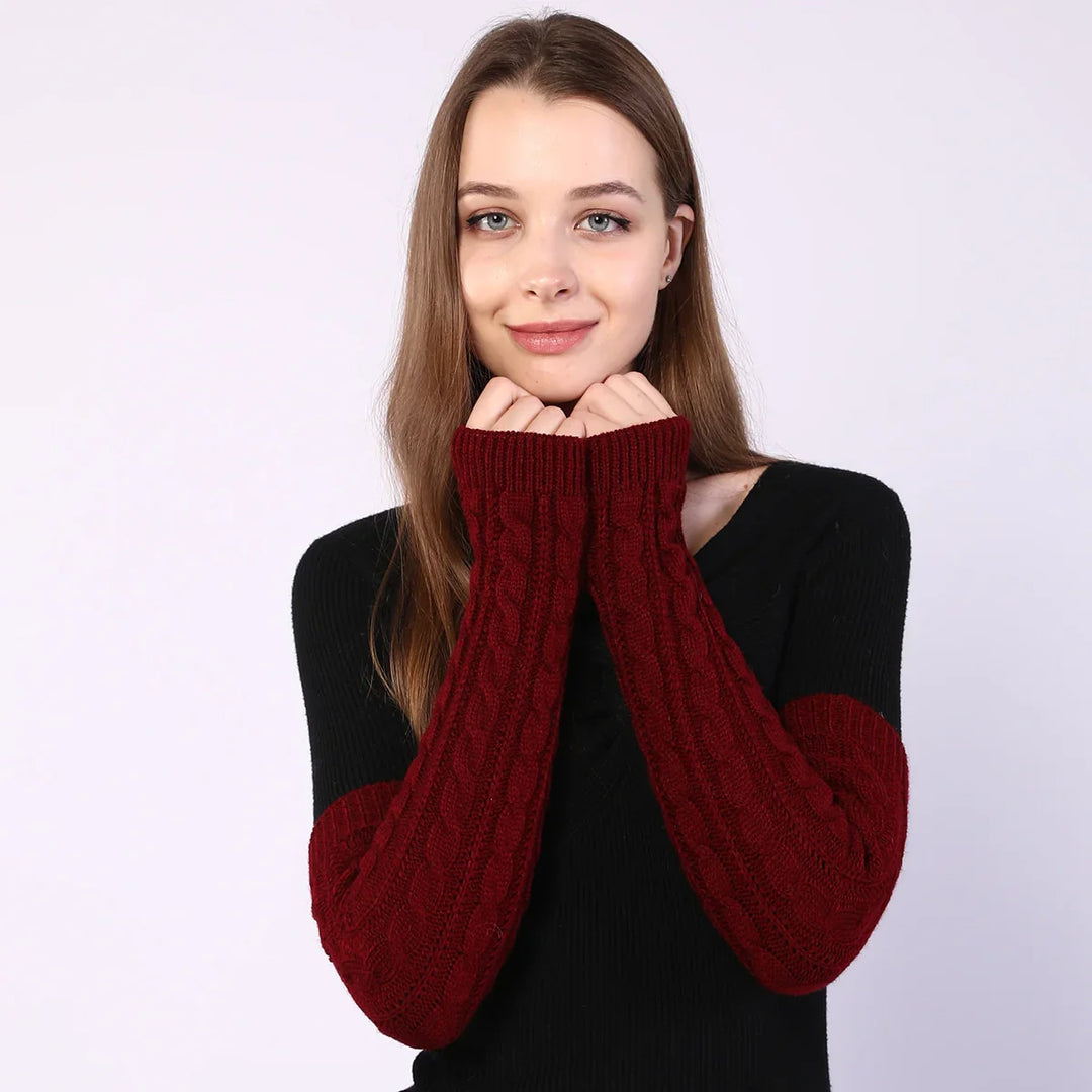 Young woman wearing black sweater with red cable knit long sleeves against light background