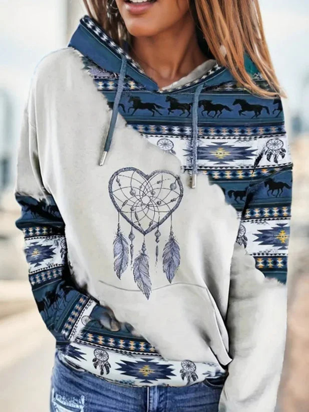 Woman wearing hoodie with heart-shaped dreamcatcher print and blue Native American horse and feather patterns