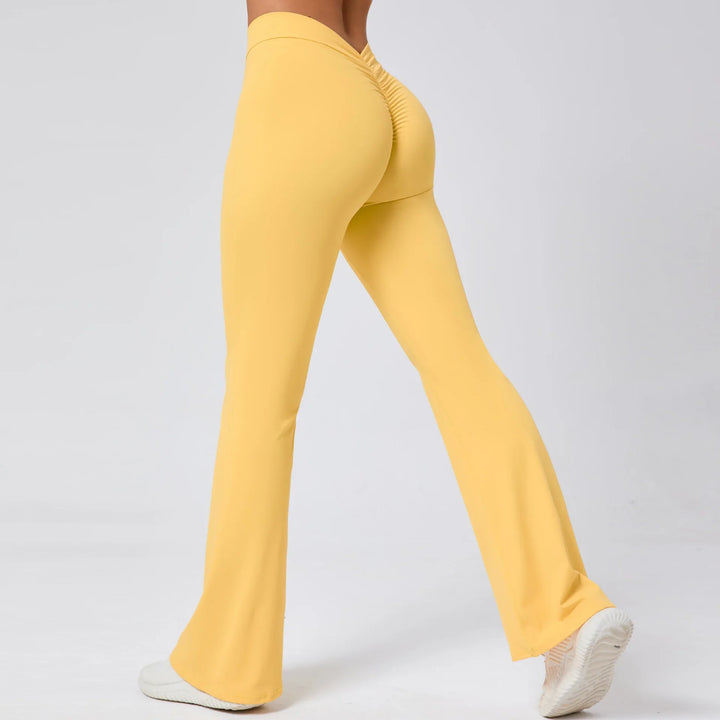 Woman wearing yellow scrunch butt fitness leggings and white sneakers on gray background