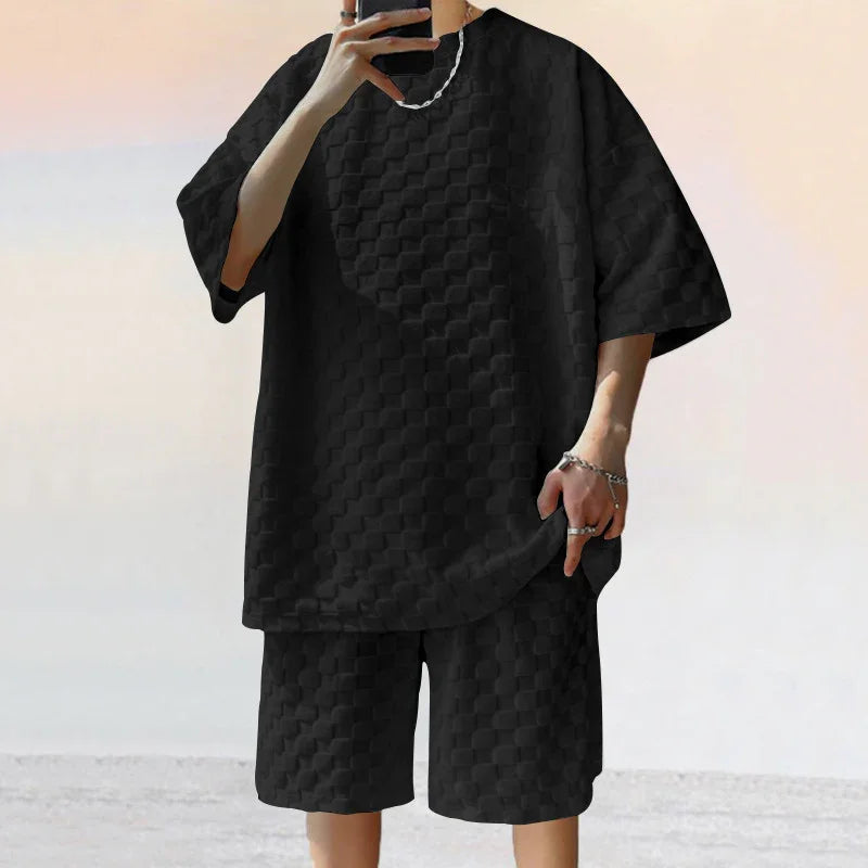 Person wearing black textured oversized T-shirt and matching shorts, casual streetwear outfit