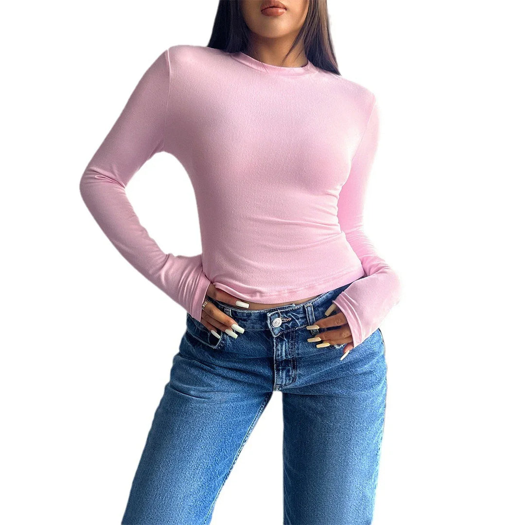 Woman wearing a fitted light pink long sleeve top and high-waisted blue jeans with natural nails