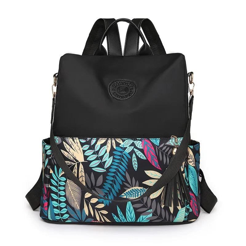 Black backpack with colorful tropical leaf print bottom and gold zipper on white background