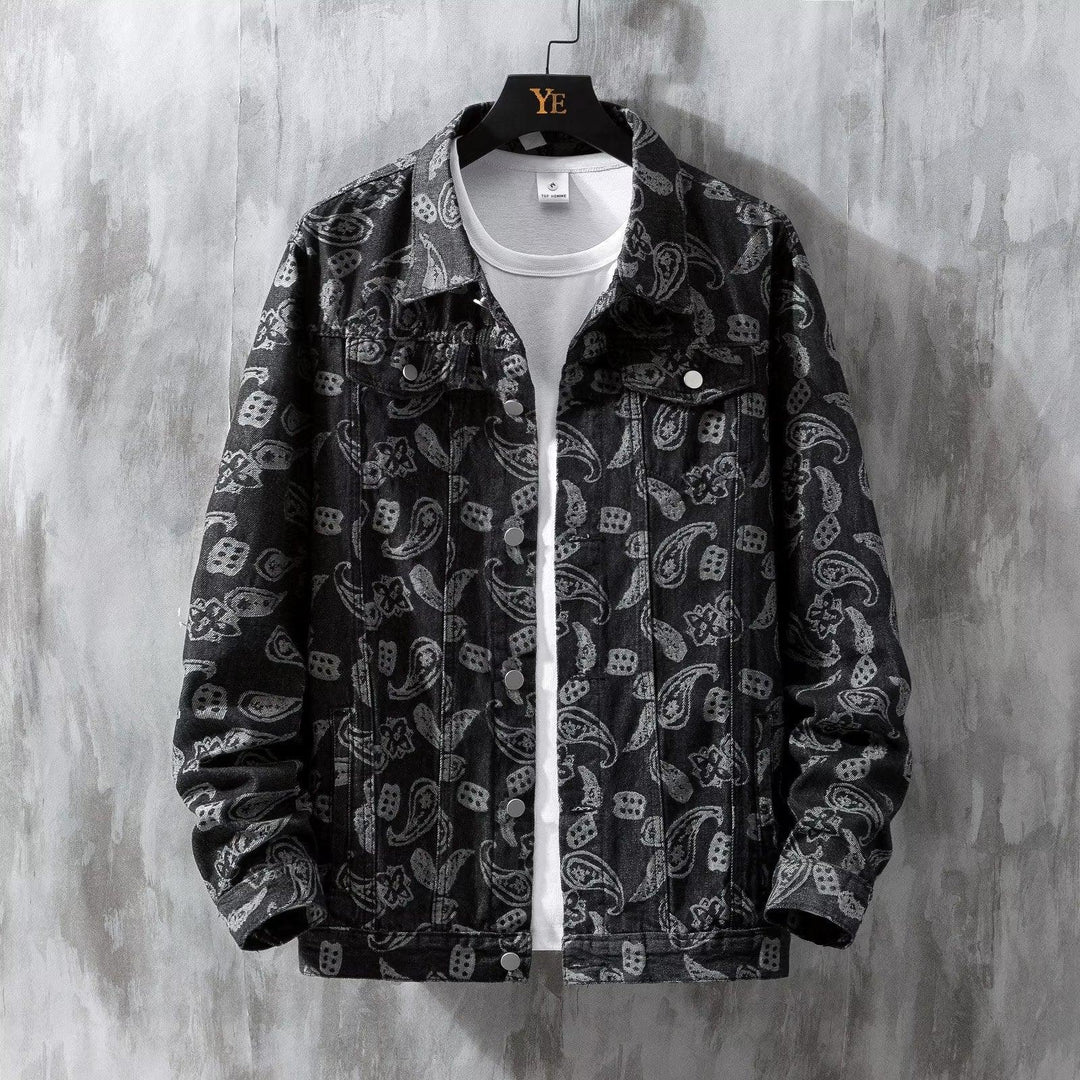 Black denim jacket with white paisley pattern over white t-shirt on black YE hanger against gray textured wall