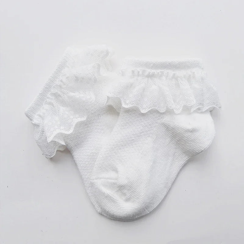 Pair of white baby socks with delicate ruffled lace trim on a white background