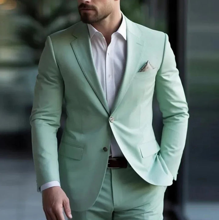 Man wearing mint green suit with white dress shirt and pocket square in modern indoor setting