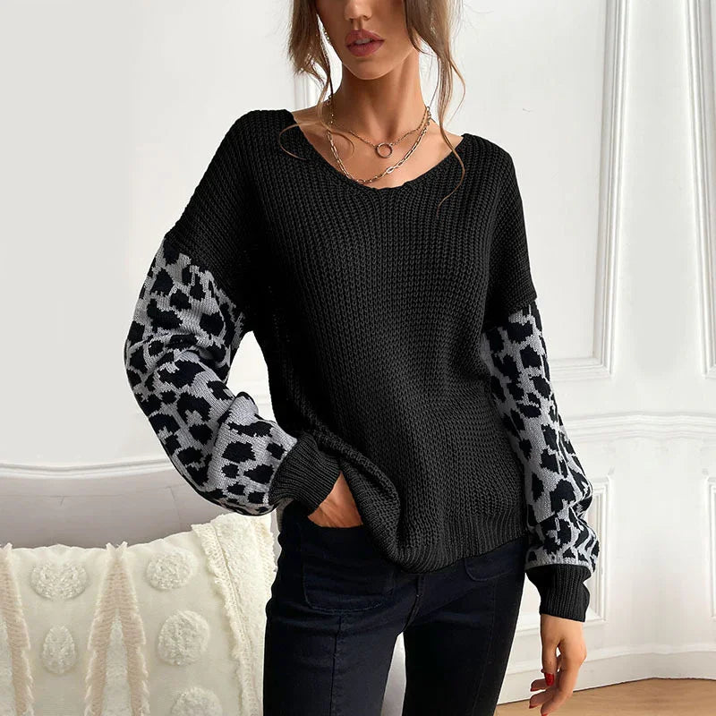 Woman wearing black knit sweater with gray leopard print balloon sleeves in bright room