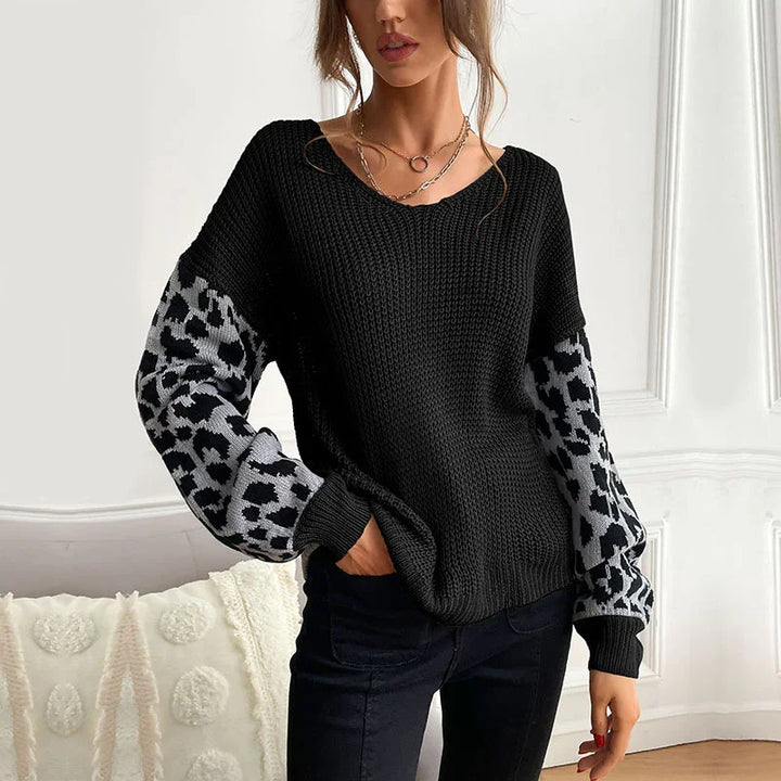 Woman wearing black knit sweater with gray leopard print balloon sleeves in bright room