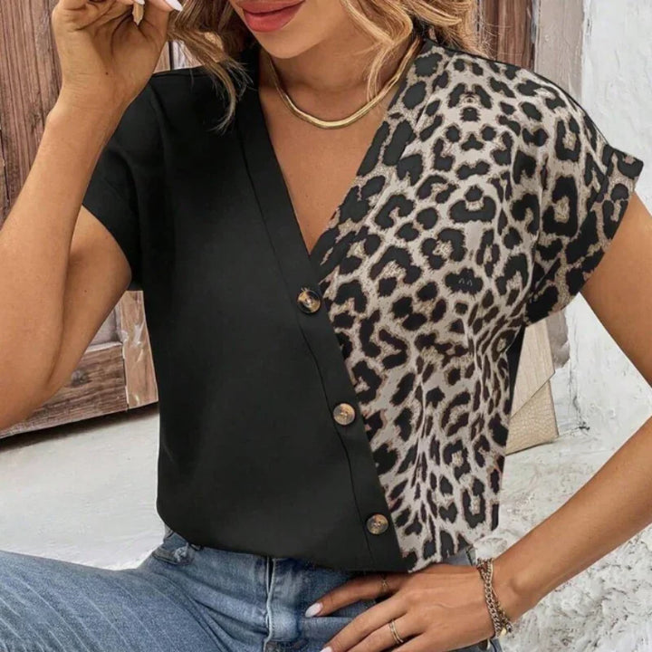 Woman wearing black and leopard print button-up short sleeve blouse with gold necklace and blue jeans