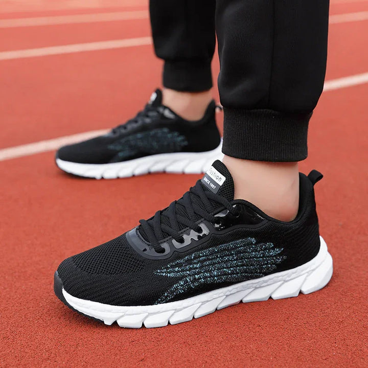 Close-up of black and white running shoes on red track surface, worn with black joggers