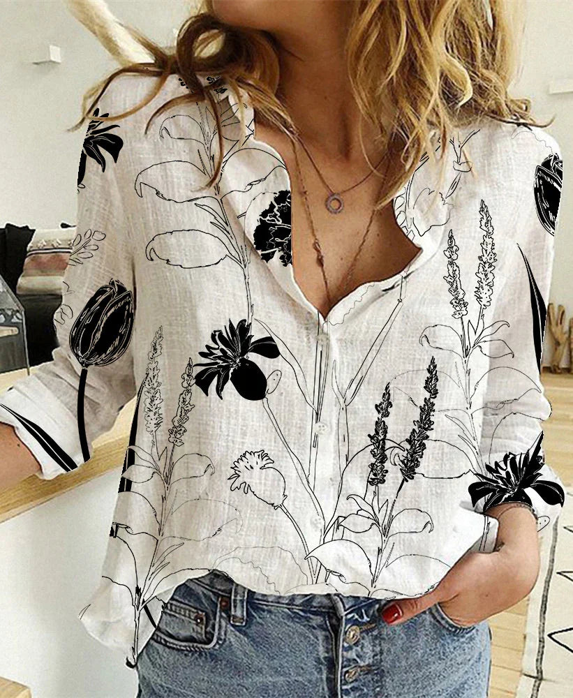 Woman wearing a white button-up blouse with black floral print and blue jeans in a modern kitchen