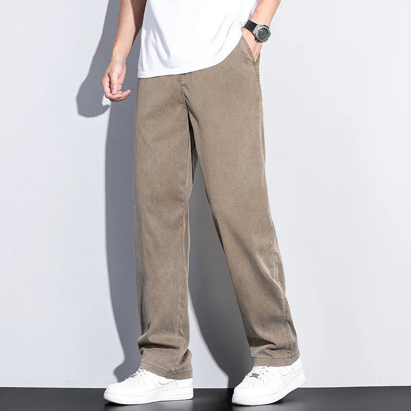 Man wearing loose-fit brown corduroy pants with white sneakers and a white t-shirt