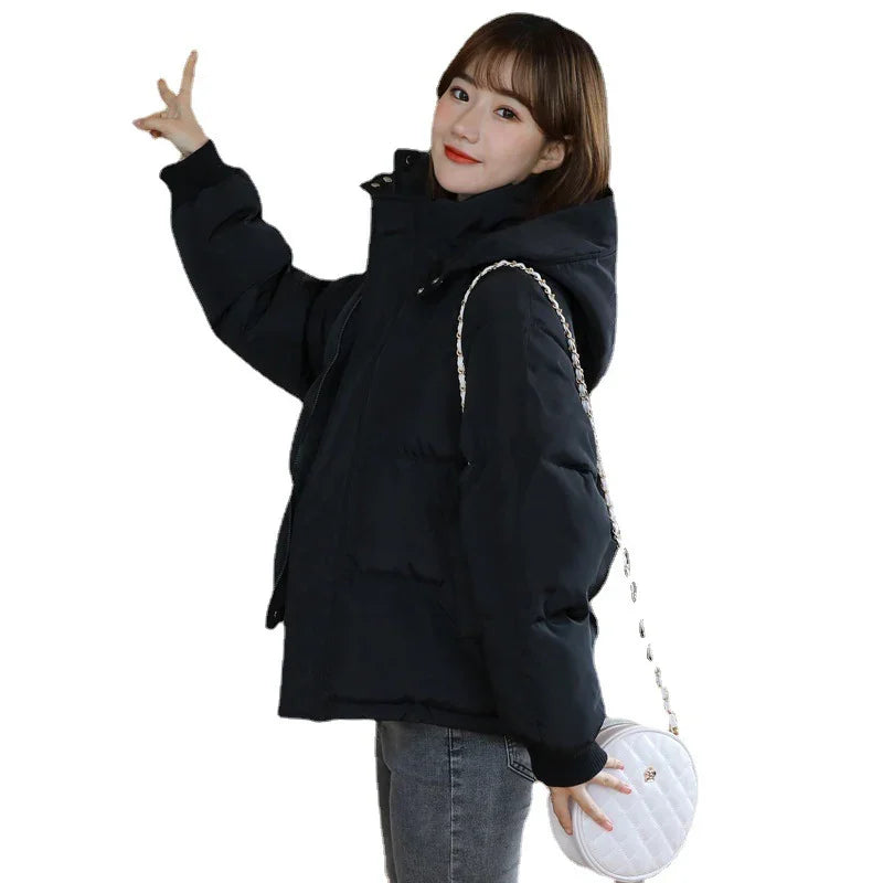 Young woman wearing black puffer jacket and gray jeans carrying white round handbag with chain strap