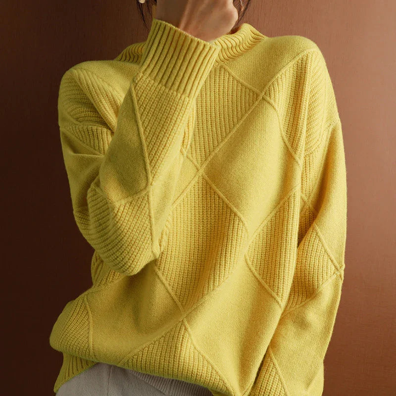Close-up of a yellow textured knit sweater with diamond patterns worn against a brown background