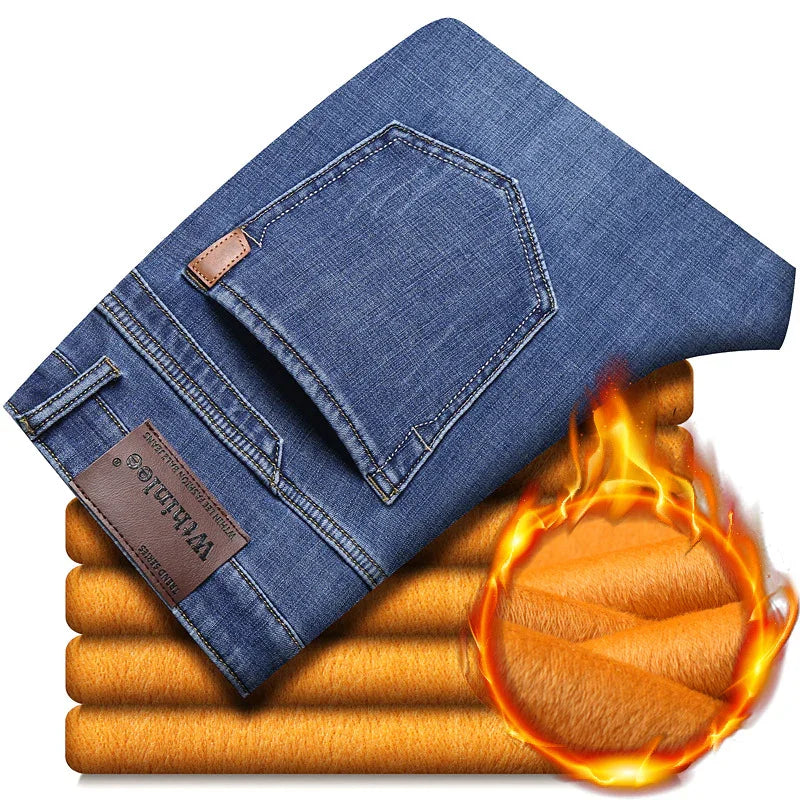 Folded blue denim jeans on warm orange fleece fabric with fire symbol indicating thermal insulation