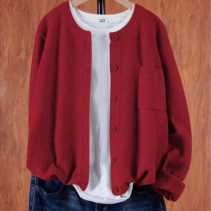 Red knitted button-up cardigan over white shirt and blue jeans on wooden background