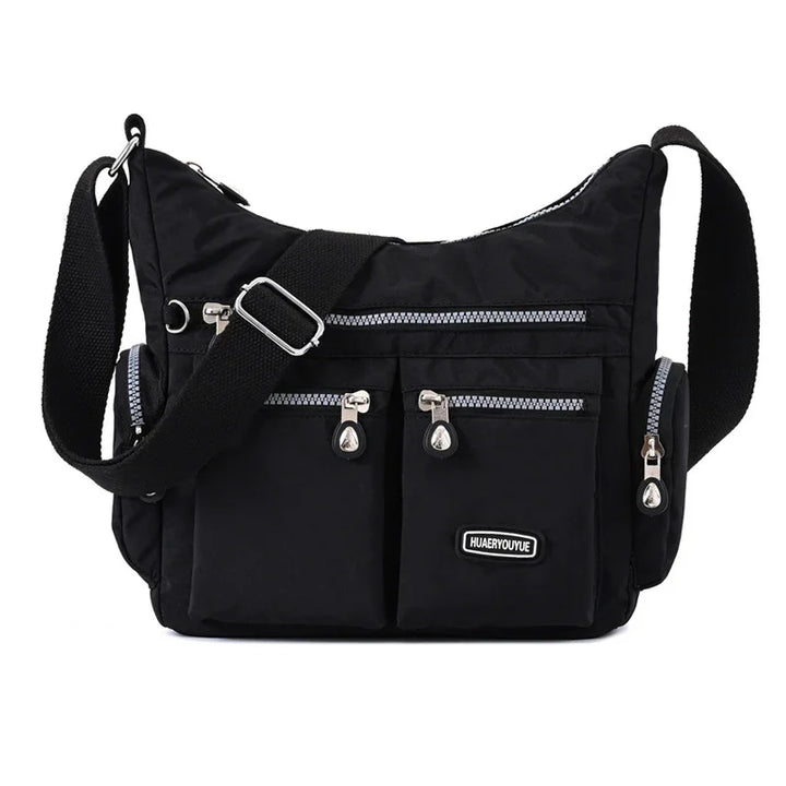 Black crossbody nylon bag with multiple zippered pockets and adjustable strap