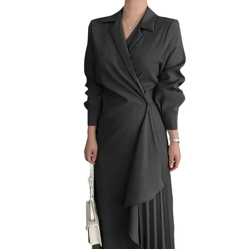 Woman wearing a stylish black wrap dress with pleated skirt detail and holding a white handbag