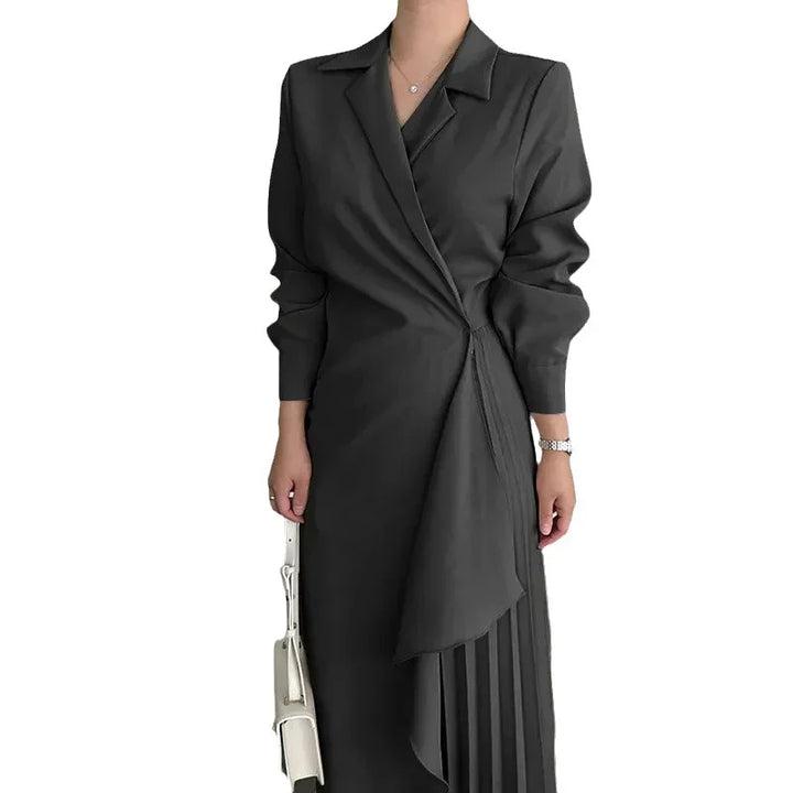 Woman wearing a stylish black wrap dress with pleated skirt detail and holding a white handbag