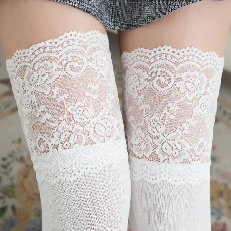 Close-up of white lace thigh-high stockings with floral patterns worn under gray skirt
