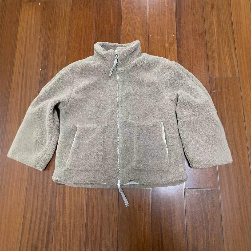 Light brown fleece jacket with full zipper and front pockets on wooden floor