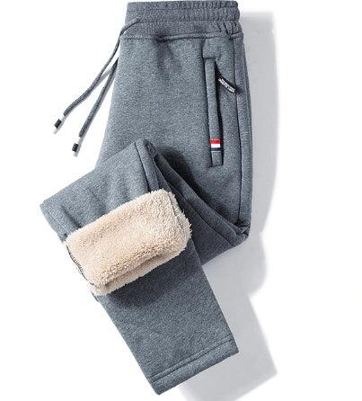 Gray fleece-lined sweatpants with drawstring waist and side pockets, folded to show soft beige inner lining