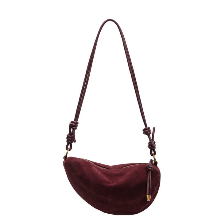 Maroon suede crescent shoulder bag with knotted strap and gold zipper pull