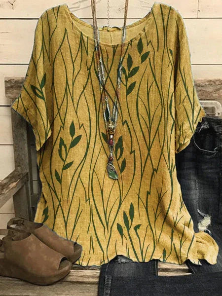 Yellow loose-fit short sleeve blouse with green leaf pattern paired with denim jeans and brown shoes