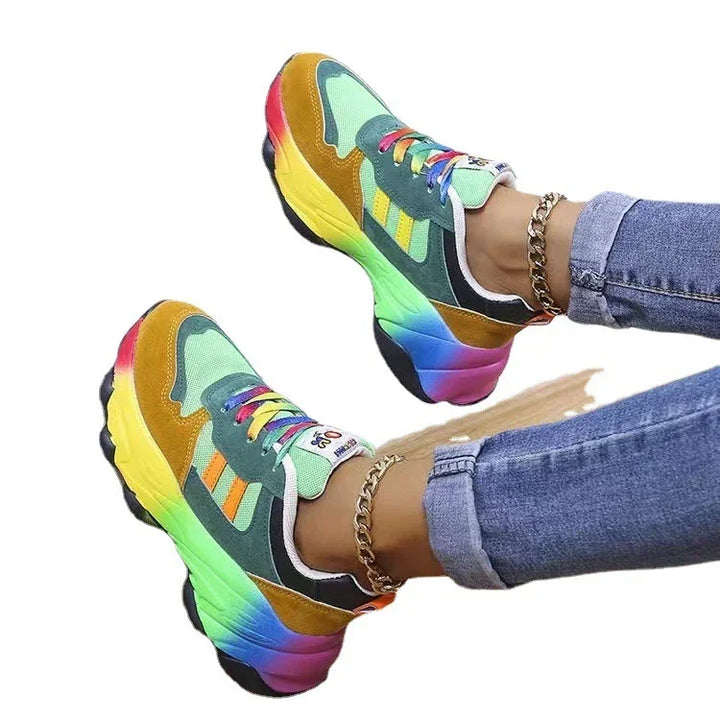 Colorful rainbow platform sneakers with blue jeans and gold chain anklets on white background