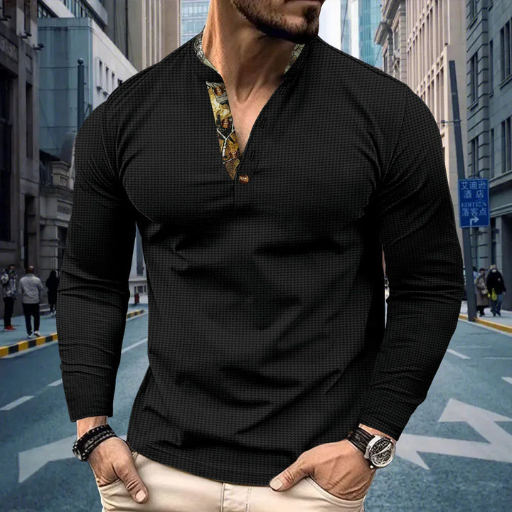 Man wearing black long-sleeve Henley shirt with patterned collar detail in urban street setting