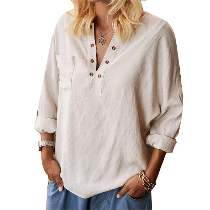 Woman wearing casual beige buttoned henley shirt with rolled sleeves and blue pants