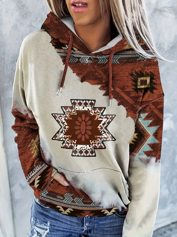 Woman wearing beige hoodie with southwestern geometric patterns in brown, white, and turquoise, paired with distressed jeans
