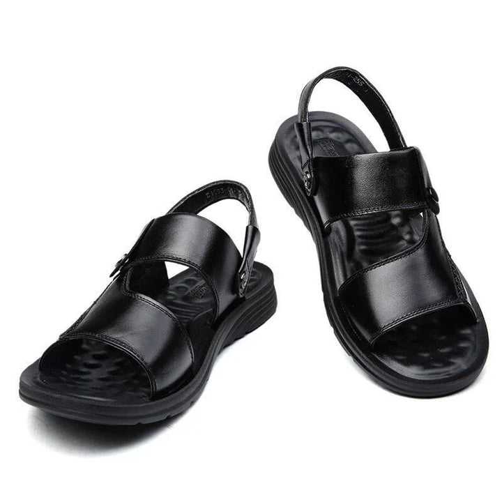 Pair of black leather sandals with adjustable straps and cushioned soles on white background